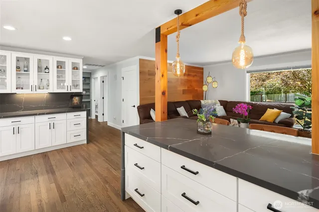 a kitchen with stainless steel appliances granite countertop a sink dishwasher and white cabinets with wooden floor