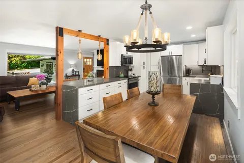 a kitchen with stainless steel appliances a dining table chairs stove and sink