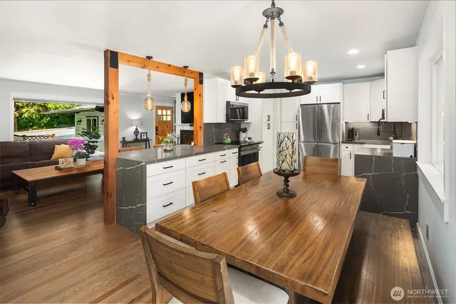 a kitchen with stainless steel appliances a dining table chairs stove and sink
