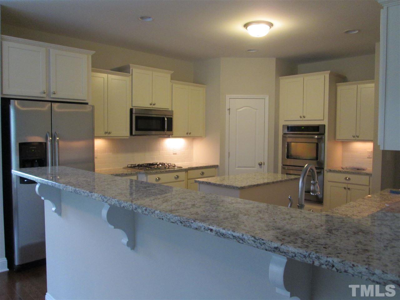 3438 Grosbeak Way Raleigh, NC 27616 - Photo 7 of 19 a kitchen with stainless steel appliances granite countertop a sink a stove and a refrigerator