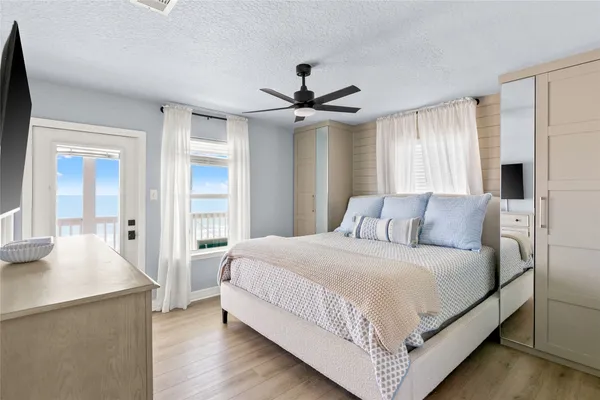 a bedroom with a large bed a chandelier and windows