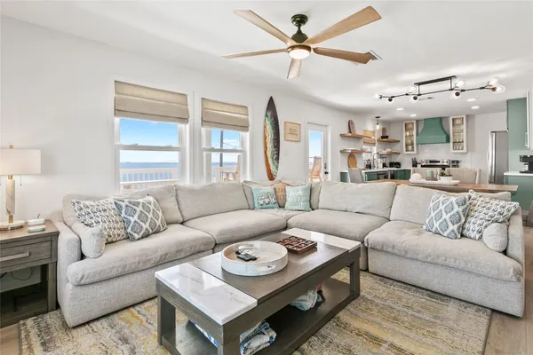 a living room with furniture a ceiling fan a rug and a window