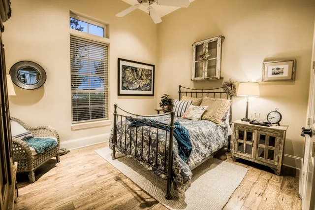 a bedroom with a bed next to a window and a lamp on dresser