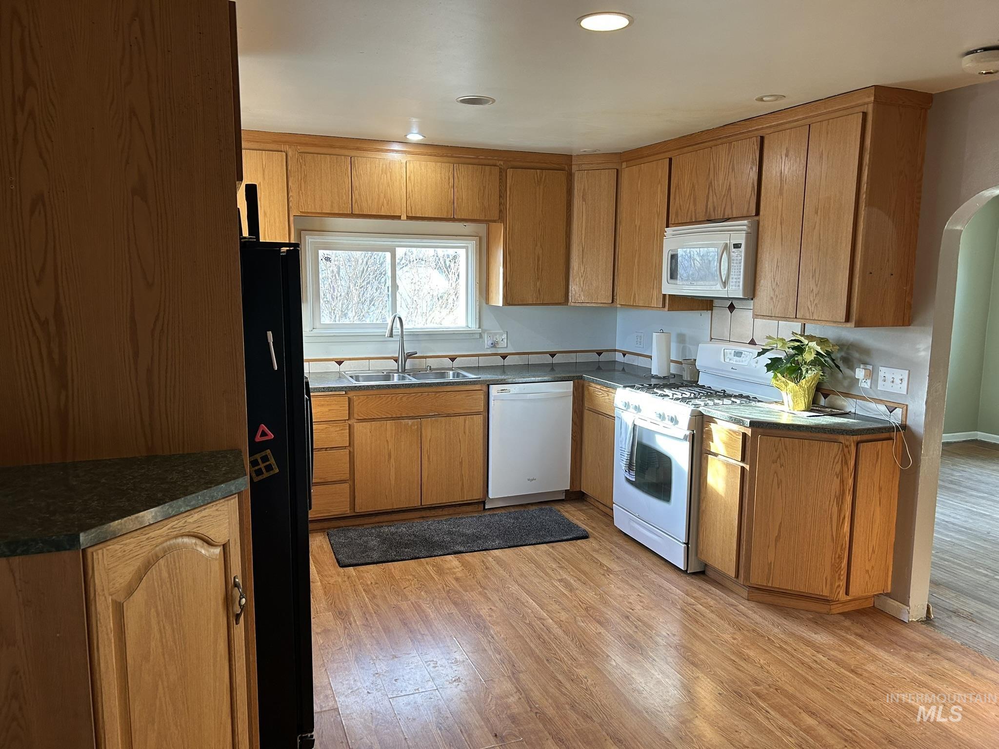 3837 16th Street Lewiston, ID 83501 - Photo 16 of 45 Kitchen with white appliances, light wood-type flooring, brown cabinetry, dark countertops, and recessed lighting