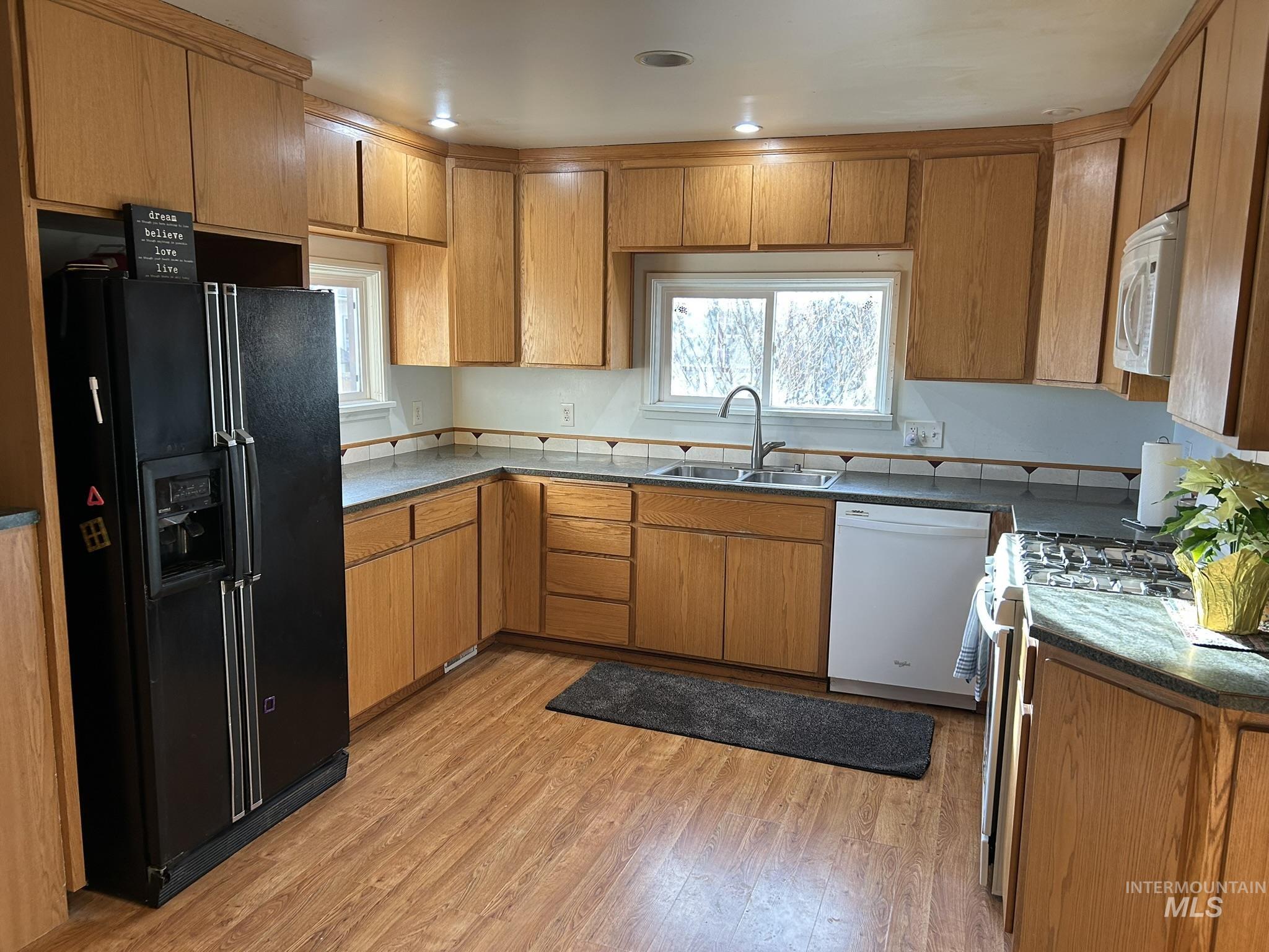 3837 16th Street Lewiston, ID 83501 - Photo 17 of 45 Kitchen with white appliances, brown cabinets, light wood-type flooring, and dark stone counters