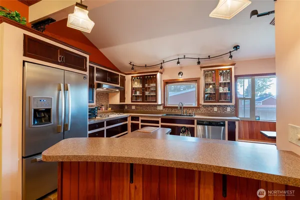 a dining hall with stainless steel appliances kitchen island a stove and a refrigerator