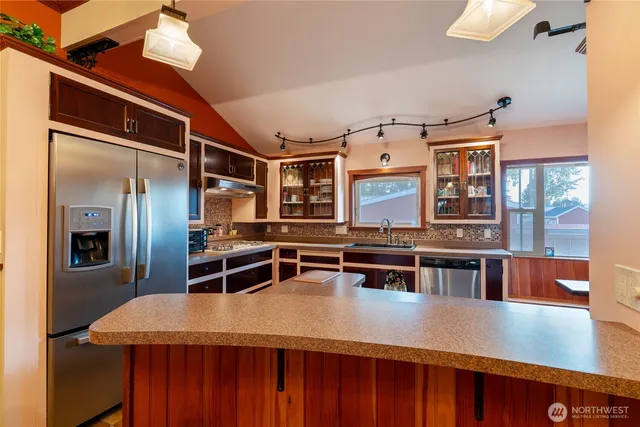 a dining hall with stainless steel appliances kitchen island a stove and a refrigerator