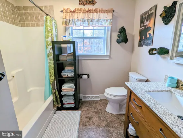 a bathroom with a granite countertop sink a large mirror and a toilet