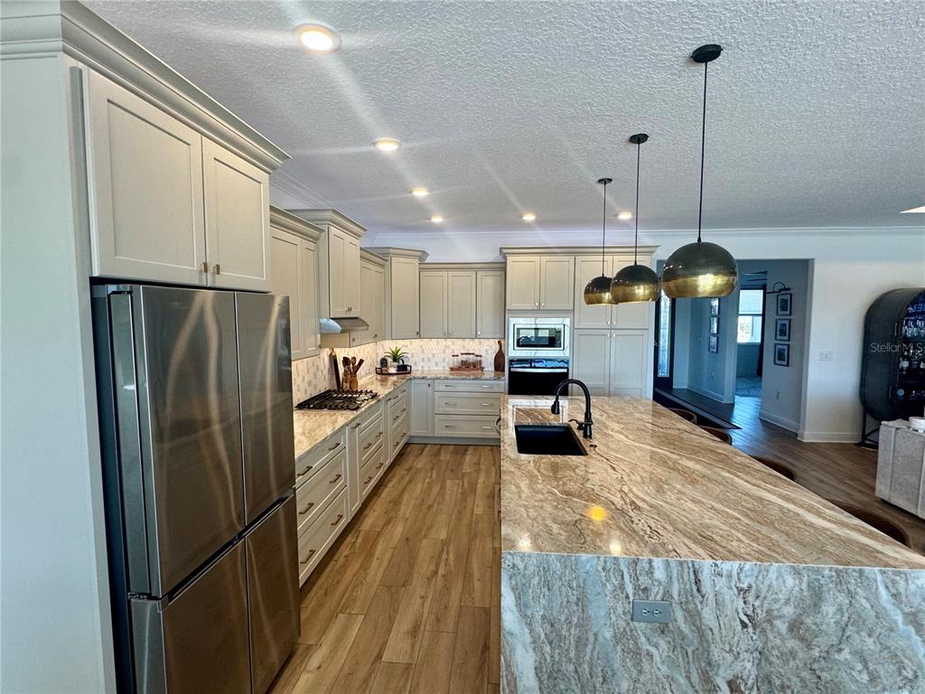 9232 Southwest 85th Place Ocala, FL 34481 - Photo 10 of 38 a kitchen with stainless steel appliances granite countertop a refrigerator a oven a sink with a countertop and chairs