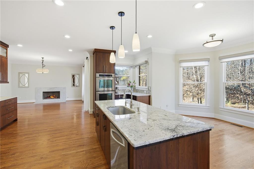 715 Crown Cove Milton, GA 30004 - Photo 17 of 102 a kitchen with stainless steel appliances granite countertop a sink a oven a dining table and chairs with wooden floor