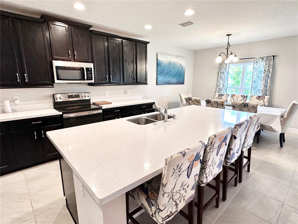 207 Petosky Road Groveland, FL 34736 - Photo 4 of 21 a kitchen with stainless steel appliances kitchen island granite countertop a stove a sink a microwave and a refrigerator