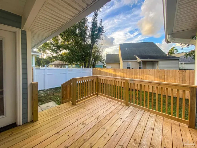 a view of a deck with wooden floor and fence next to a yard