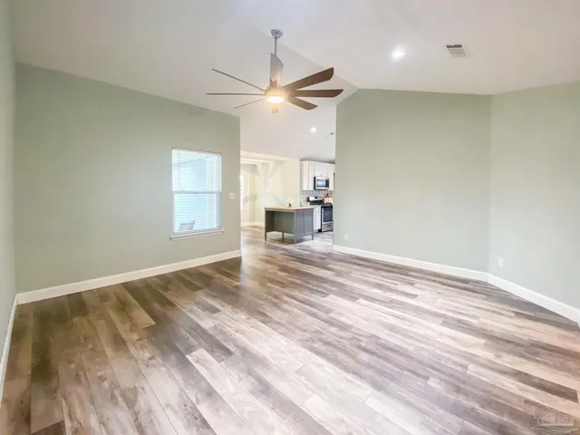 a view of empty room with wooden floor and fan