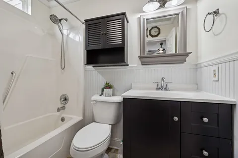 a bathroom with a toilet sink vanity tub and mirror