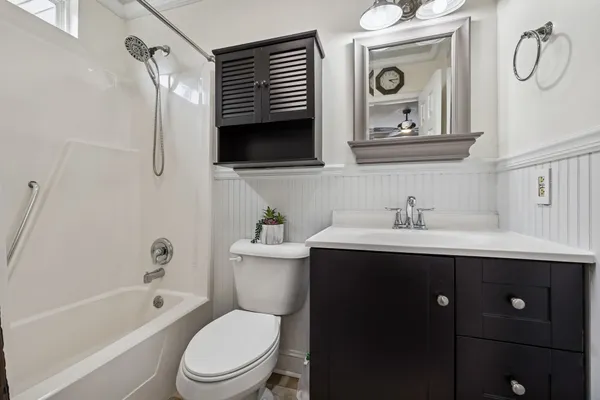 a bathroom with a toilet sink vanity tub and mirror