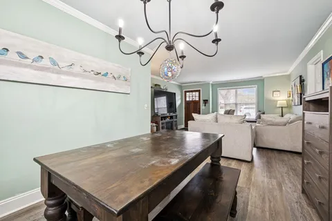 a view of a dining room and livingroom with furniture wooden floor a chandelier