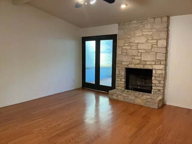 an empty room with wooden floor fireplace and windows