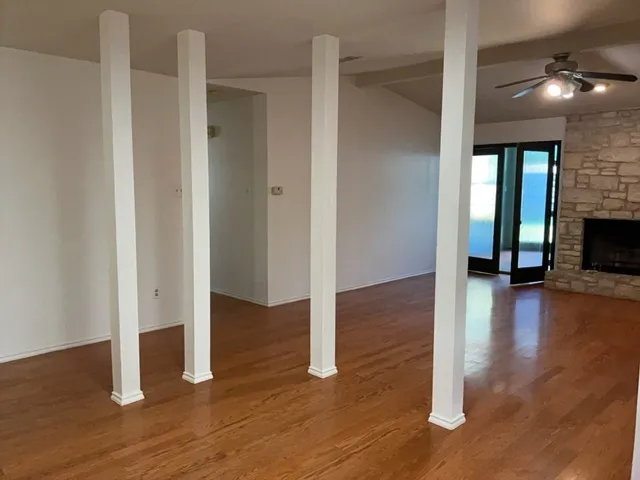 an empty room with wooden floor fireplace and windows