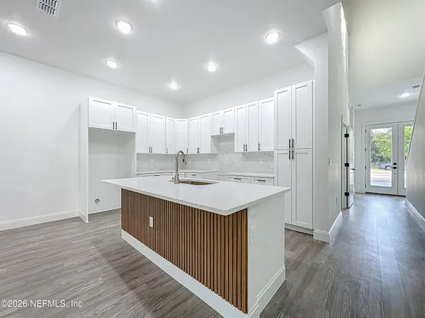 an empty room with wooden floor cabinet and windows