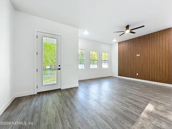 an empty room with wooden floor and kitchen view