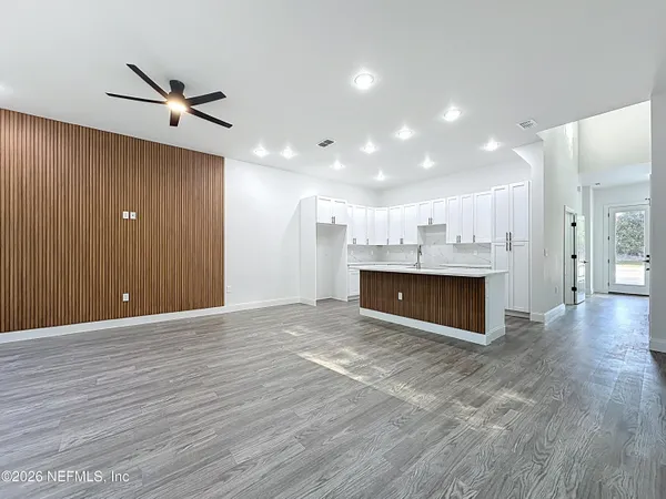 a view of a hallway with wooden floor and a bathroom
