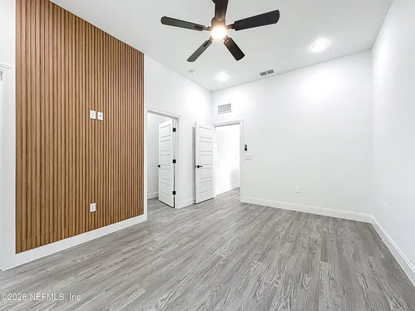 a view of empty room with wooden floor and fan