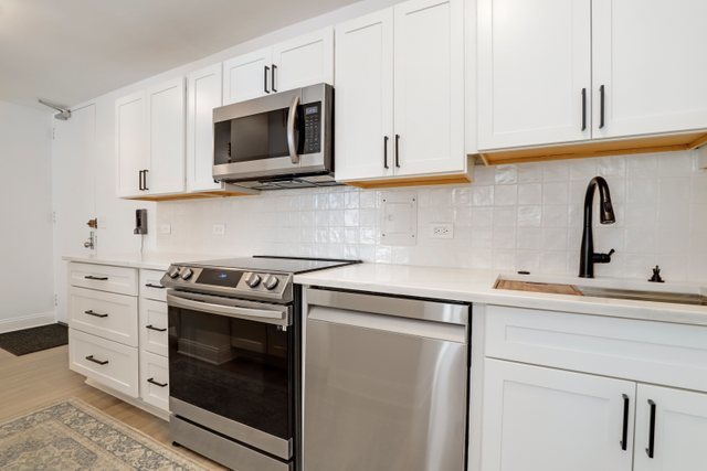 5701 North Sheridan Road, Unit 4R Chicago, IL 60660 - Photo 10 of 18 a kitchen with cabinets stainless steel appliances and wooden floor