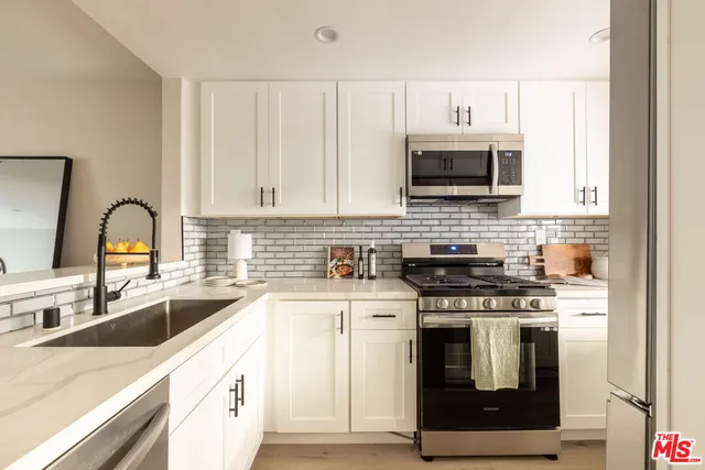 a kitchen with stainless steel appliances granite countertop a stove sink and microwave