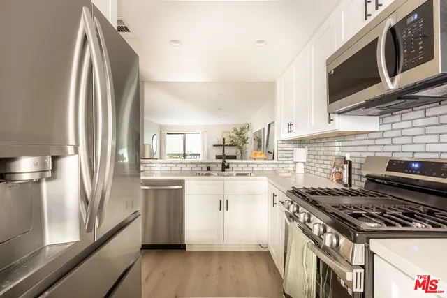 a kitchen with stainless steel appliances a stove a sink and white cabinets