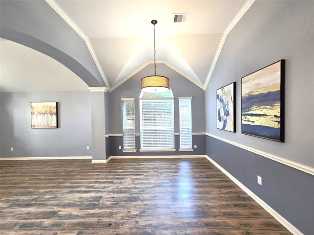 a view of an empty room with window and wooden floor