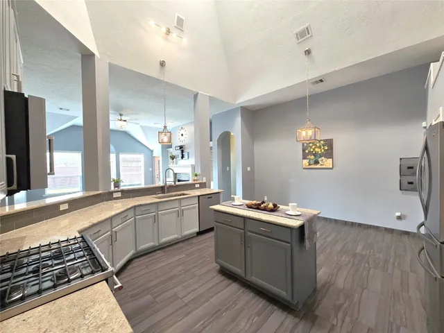 a room with stainless steel appliances kitchen island granite countertop a stove a sink and a refrigerator
