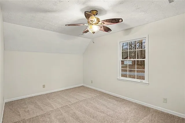 an empty room with window and ceiling fan