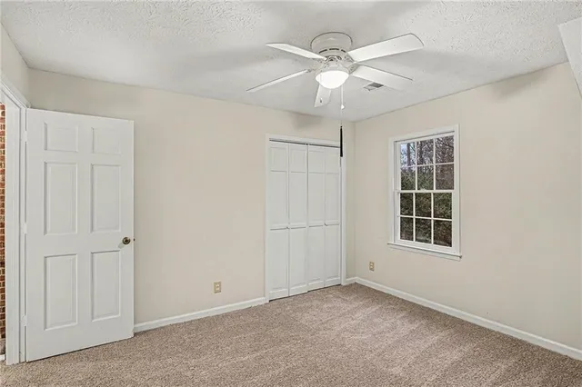 an empty room with windows and fan