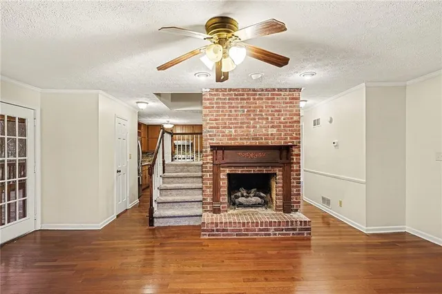 a view of an empty room with wooden floor fireplace and a window