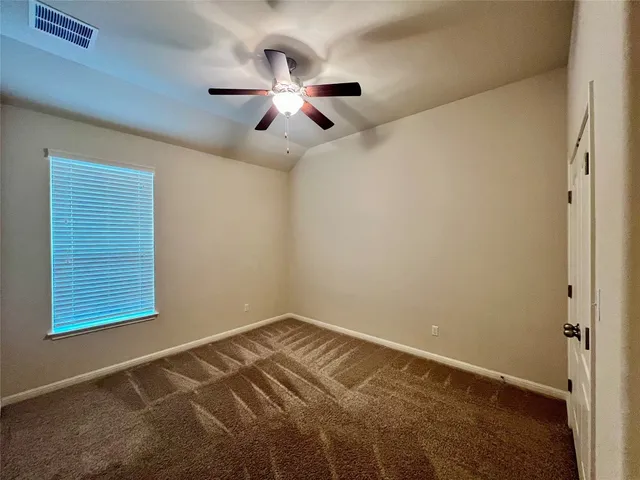 an empty room with windows and fan