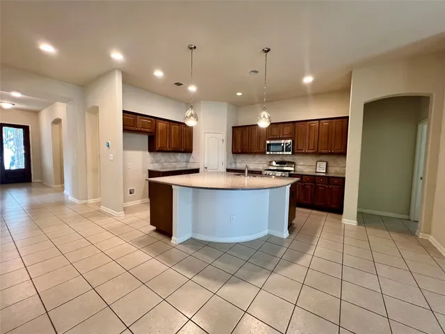 a large kitchen with stainless steel appliances lots of counter top space cabinets and a view of kitchen