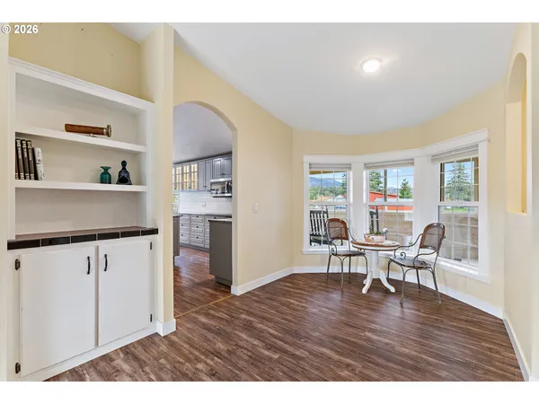 a open kitchen with stainless steel appliances granite countertop a stove top oven a dining table and chairs with wooden floor