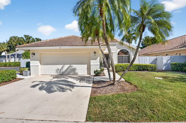 a view of a house with a yard and palm trees