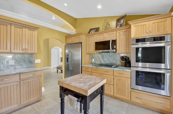 a kitchen with stainless steel appliances granite countertop a refrigerator a stove and a sink