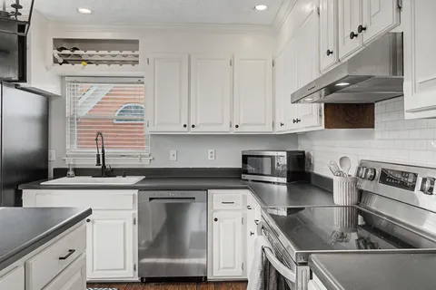 a kitchen with granite countertop a sink stainless steel appliances and cabinets