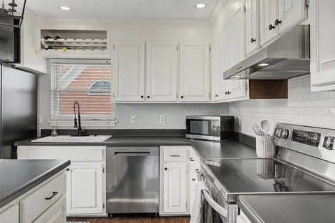 a kitchen with granite countertop a sink stainless steel appliances and cabinets