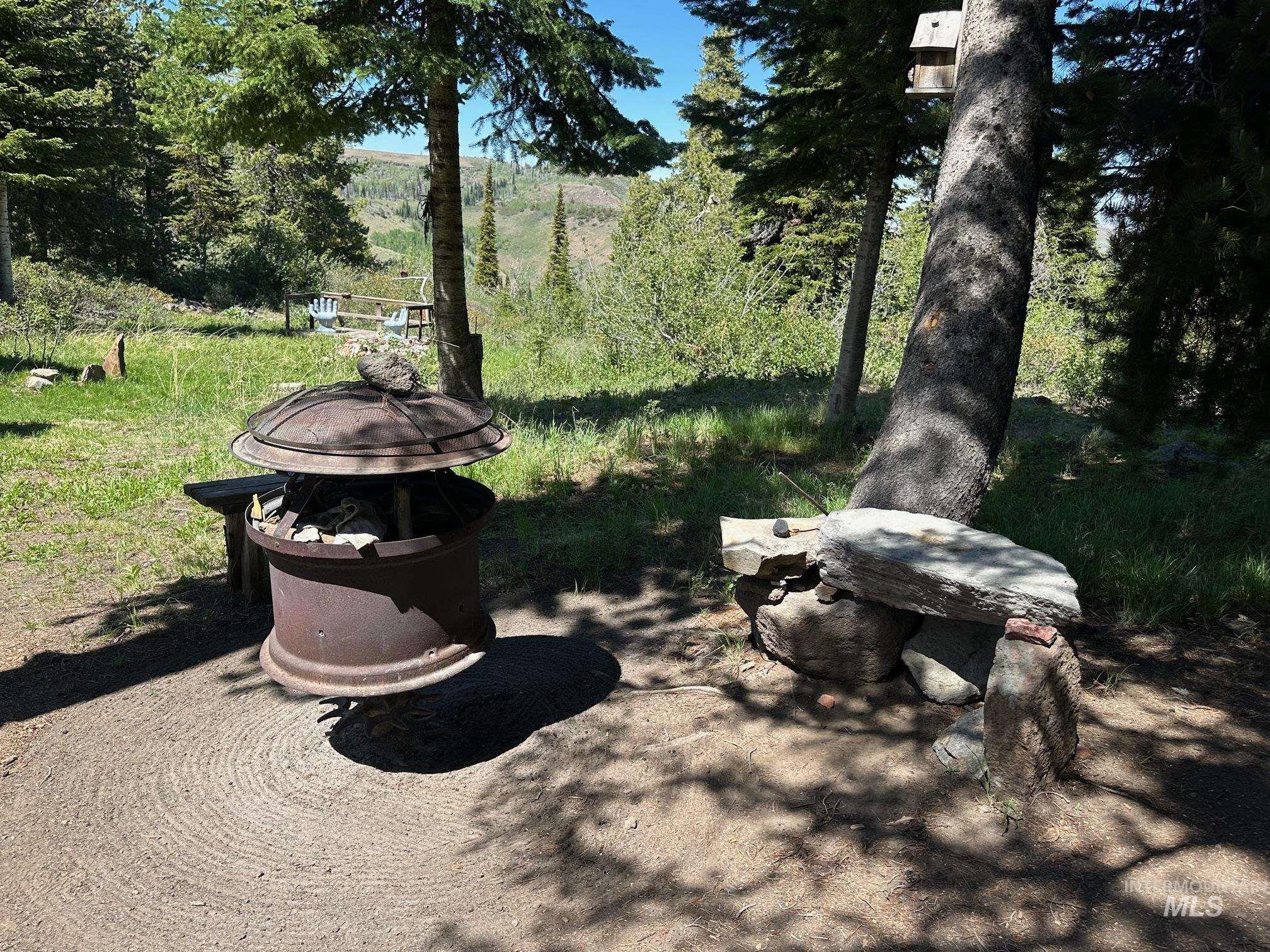509 Deadline Road, Unit 2 Twin Falls, ID 83301 - Photo 26 of 28 Outdoor fire pit area featuring a circular dirt pad, a metal fire pit with a cover, and stone seating