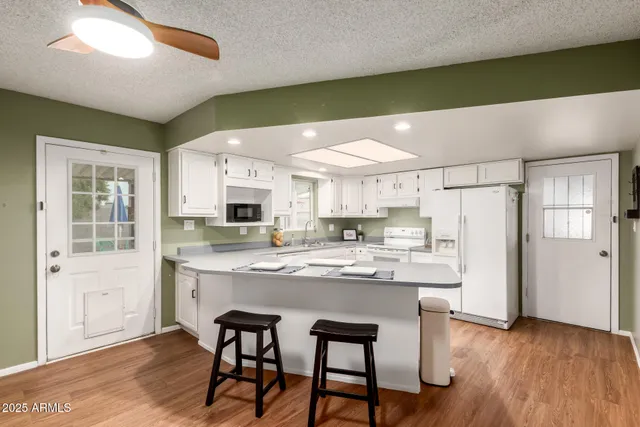 a kitchen with stainless steel appliances kitchen island granite countertop a table chairs and a refrigerator
