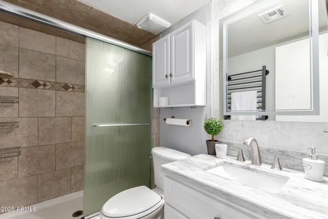 a bathroom with a granite countertop sink a toilet and shower