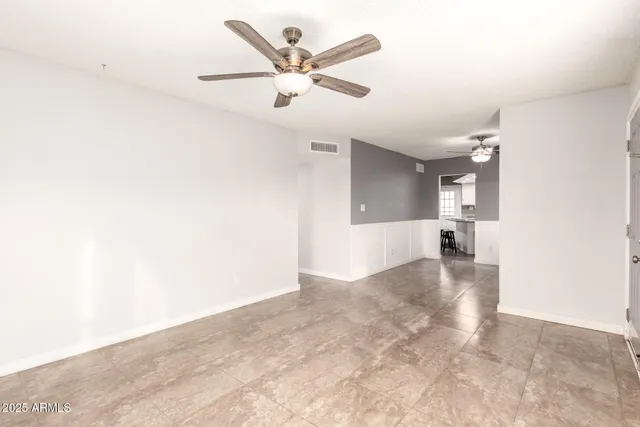 an empty room with wooden floor and a ceiling fan