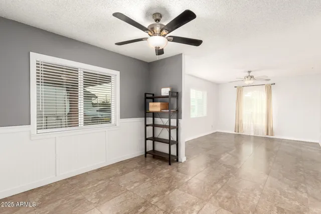 a view of an empty room with a window and a ceiling fan