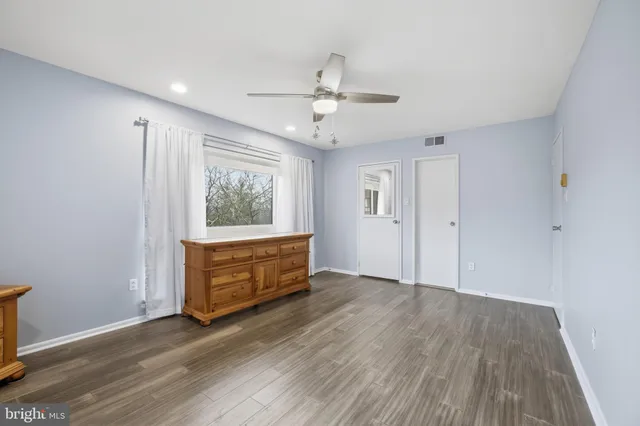 an empty room with wooden floor cabinet and windows