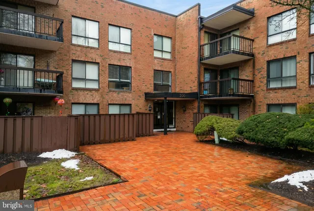 a view of a brick house with many windows plants and a yard
