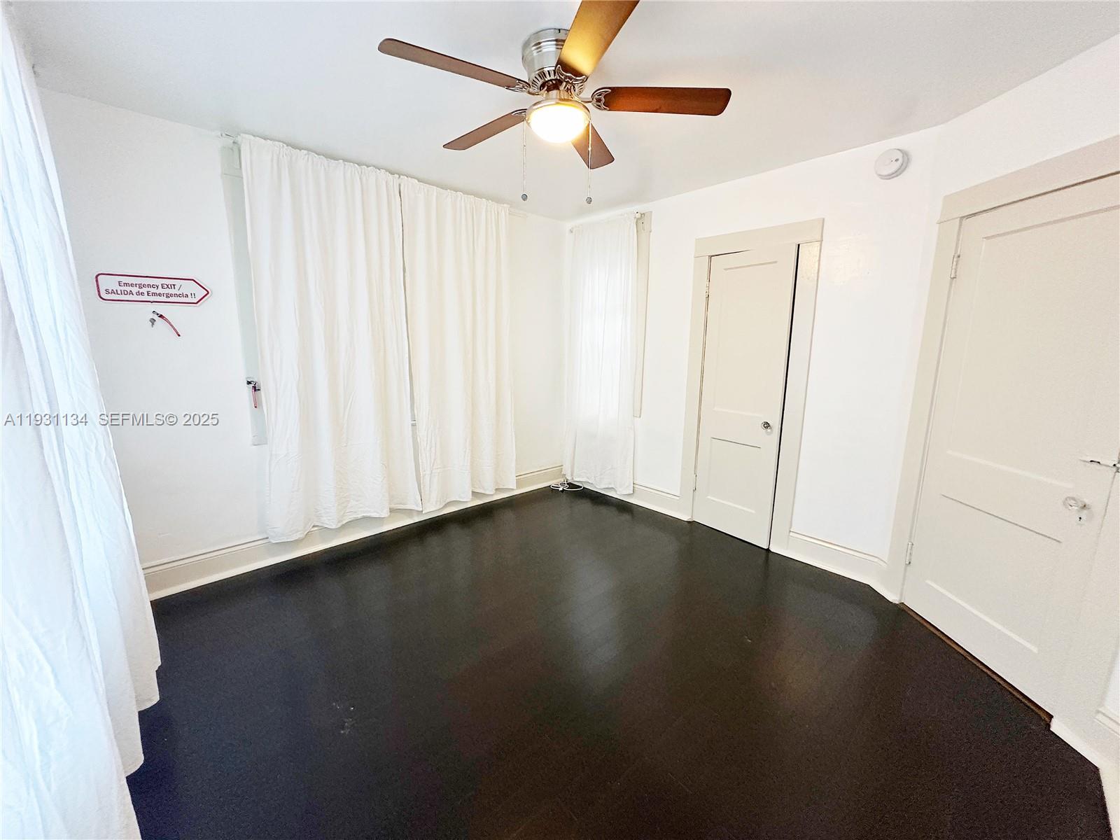 2153 Southwest 14th Terrace, Unit 1 Miami, FL 33145 - Photo 8 of 17 an empty room with wooden floor fan and windows