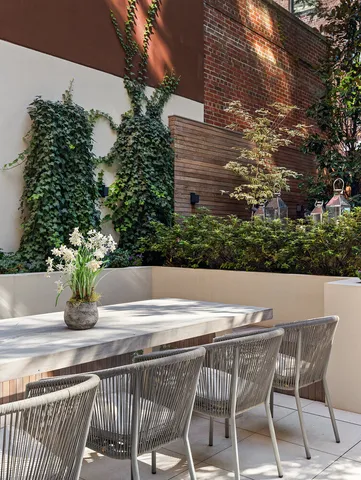 a view of patio with table and chairs under an umbrella with large trees